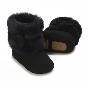 Close-up of black baby winter boots with fluffy fur trim and decorative bow detail