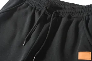 Detail of black men's casual pants showing elastic drawstring waist and leather patch