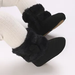 Detailed view of baby black faux fur winter boots with bow and soft sole for newborns.