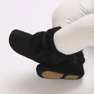 Detailed close-up of black infant winter boots featuring soft fur lining and bow accent