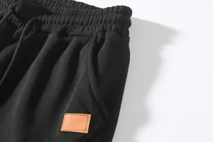 Detail view of black men's casual joggers with drawstring waist and leather patch