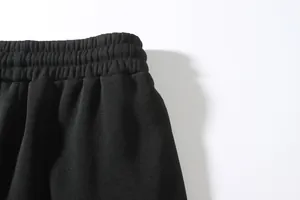 Detailed close-up view of the elastic waistband on black joggers showing stitching