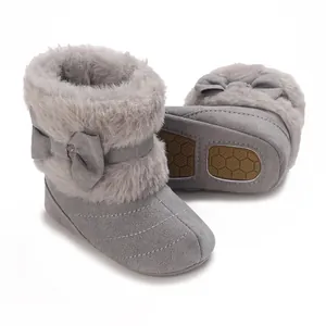 Close-up view of grey baby winter boots with fluffy fur trim and cute decorative bow