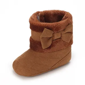 Detail view of brown plush-lined baby boots with a decorative bow for autumn and winter.