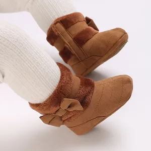 Detailed view of brown plush baby boots with soft soles and decorative bows