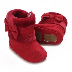 Close-up of red baby winter boots with soft plush lining and bow decoration