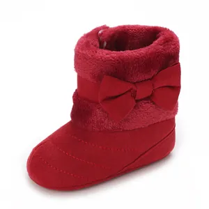 Detail view of soft-soled red baby bootie with a cute plush bow for winter warmth.