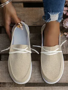 Detailed macro view of beige canvas women's loafers with white laces on wooden background
