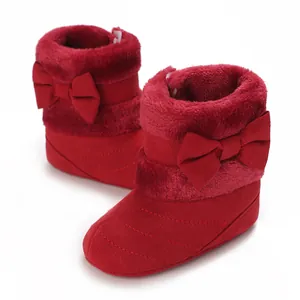 Detailed view of red infant soft sole boots with plush trim and decorative bow