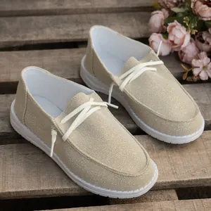 Close-up of shimmering beige canvas loafers featuring white elastic laces on rustic wood
