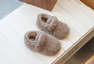 Chaussons pour bébé en polaire marron pour l'hiver présentés sur des lattes en bois