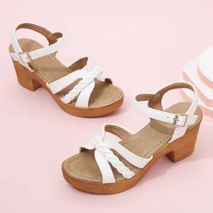 White chunky heel sandals with braided straps and ankle buckle on pink background