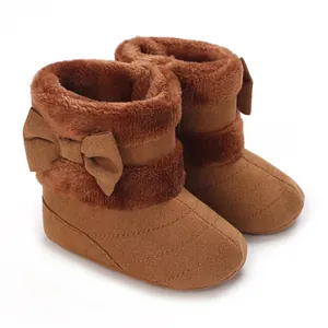 Close-up detail of brown baby winter boots featuring plush fur trim and decorative bows