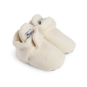 Close-up of soft white fleece baby walking booties with non-slip soles for winter warmth