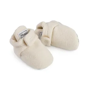 Detailed close-up view of cream white soft fleece winter baby booties with velcro strap