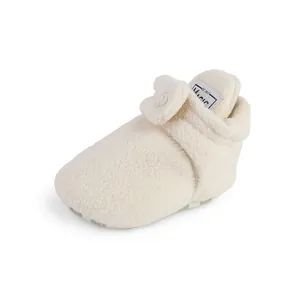 Close-up detail of warm cream fleece baby booties with adjustable velcro strap closure