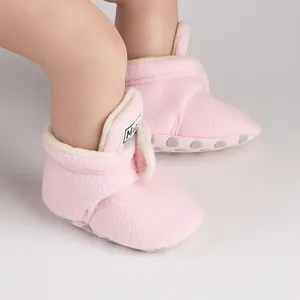 Close-up of pink fleece winter baby walker shoes on legs with soft non-slip soles