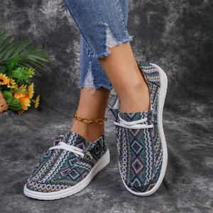 Detail of women's ethnic pattern canvas loafers with white sole and ripped jeans.
