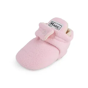 Close-up of soft pink fleece baby bootie with adjustable Velcro strap and plush lining.