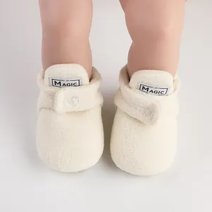Close-up macro view of cream fuzzy baby winter boots featuring a small MAGIC woven label