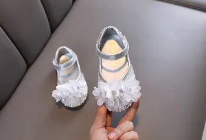 Detail view of sparkly silver girl's princess shoes with rhinestones and white floral accents.