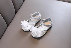 Detail view of sparkling silver rhinestone princess shoes with white floral accents