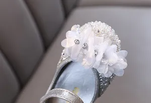Detail view of sparkling rhinestones and white fabric flowers on girl's princess shoes