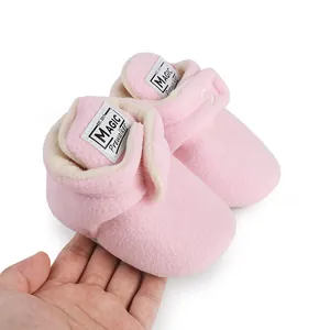 Close-up detail of soft pink fleece baby pre-walker boots held in hand for winter warmth