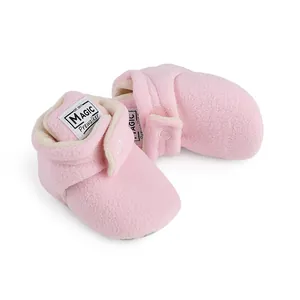 Detailed view of cozy pink fleece baby booties with adjustable hook and loop straps