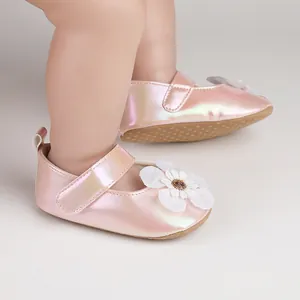 Detailansicht der irisierenden rosa Babylauflernschuhe mit weißer Blume am Fuß.