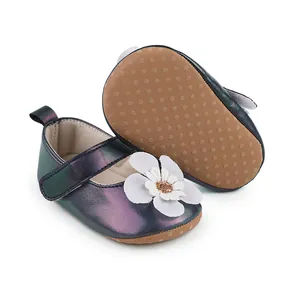 Detailansicht schillernder Lauflernschuhe für Babys mit weißer Blumendekoration.