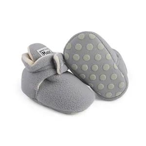 Close-up view of grey fleece baby booties featuring anti-slip dotted sole for infants and toddlers