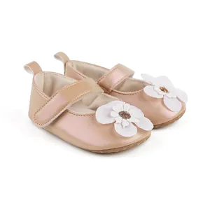 Detailaufnahme von roségoldenen Lauflernschuhen mit einer zarten weißen Blume
