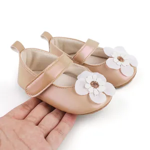 Nahaufnahme weicher rosa Baby-Lauflernschuhe mit weißer Blüte, in der Hand gehalten
