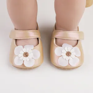 Detail von champagnerfarbenen Babyschuhen mit weißer Stoffblume und Perlmuttglanz