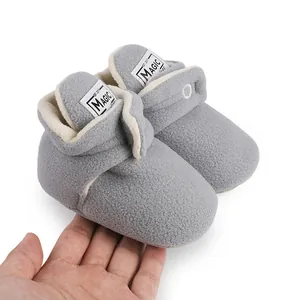 Close-up of grey fleece baby winter boots held by hand to show soft texture and size.