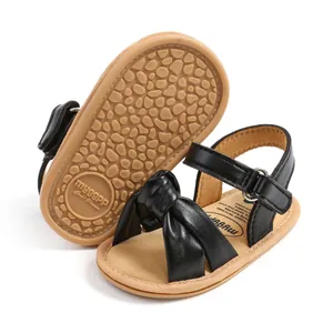 Detailopname van de zachte antislipzool en zwarte strikband van deze schattige baby sandaaltjes