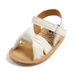 Detailopname van deze witte babysandalen met een zachte zool en schattige strik.