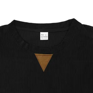 Close-up view of black corduroy sweatshirt collar with brown accent and white size tag