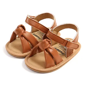 Klassieke bruine baby sandalen met zachte zool en een decoratief knoopdetail op de band