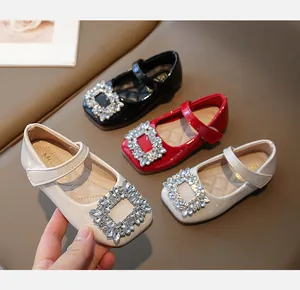 Close-up of girls' square toe patent leather shoes with large rhinestone buckle
