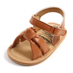 Detailopname van bruine babysandalen met geknoopte band en zachte binnenzool.
