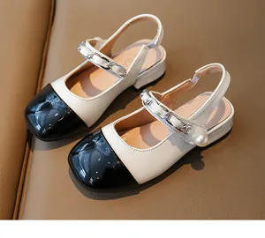 Close-up detail of girl's two-tone patent leather sandals with pearl and chain strap decoration