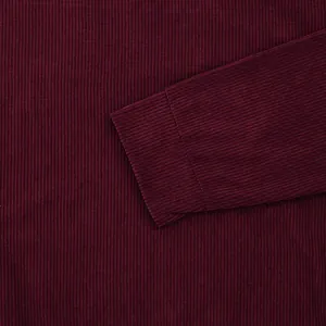 Detailed close-up showing the soft burgundy corduroy fabric texture on a garment sleeve
