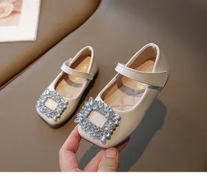 Close-up of beige patent leather Mary Jane shoes with square rhinestone buckle detail