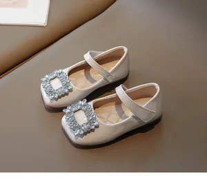 Close-up of girls beige patent leather princess shoes with sparkly rhinestone buckle