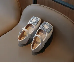Detail view of cream patent leather girls' shoes with large square rhinestone buckles