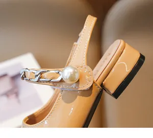 Close-up of girls' apricot patent leather sandal featuring pearl and silver chain detail