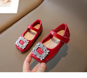 Macro detail of red patent leather girls' princess shoes featuring sparkling rhinestone buckles