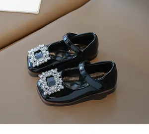 Detailed view of girl's black patent leather Mary Jane shoes with rhinestone square buckle.